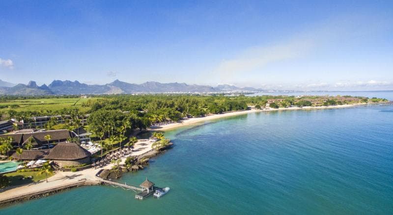 Le Maritim vu du ciel : côte bordée d'arbres, ponton sur la baie et montagnes au loin