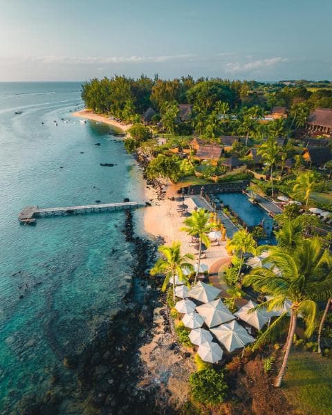 L'Oberoi vu du ciel : jetée sur le lagon, pavillons dans la verdure et parasols le long du rivage
