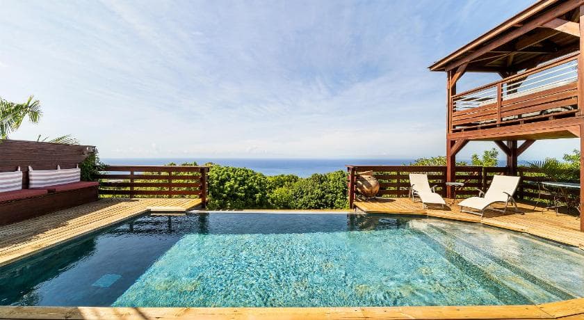 Piscine à débordement de La Plantation, transats sur la terrasse en bois et océan Indien à l'horizon