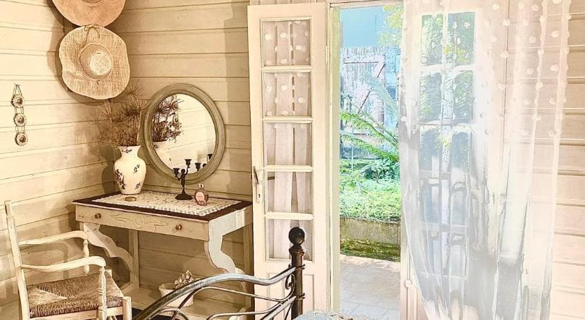 Coiffeuse à miroir rond et murs lambrissés dans une chambre de La Kaz Langevin, porte ouverte sur le jardin