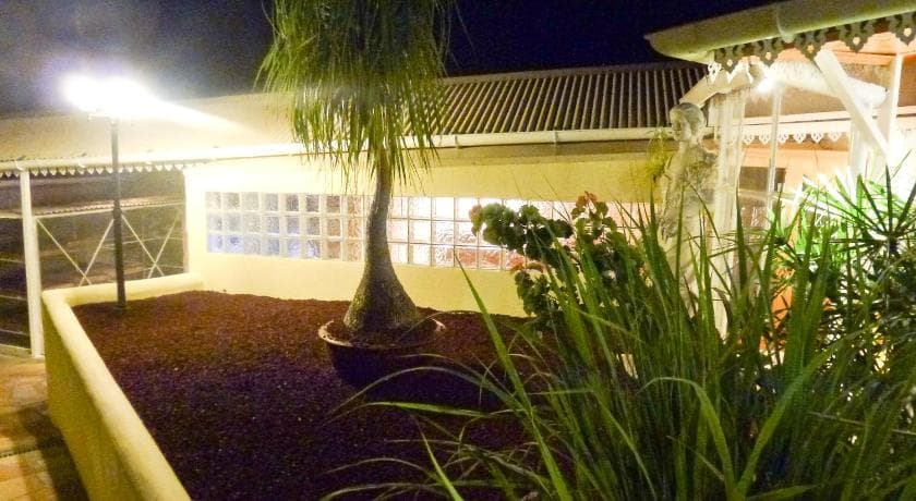 Jardin éclairé de nuit à La Résidence des Caféiers, palmier en pot et maison créole