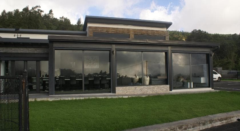 Maison des Quatre Saisons, grande véranda vitrée sur une pelouse, forêt en arrière-plan