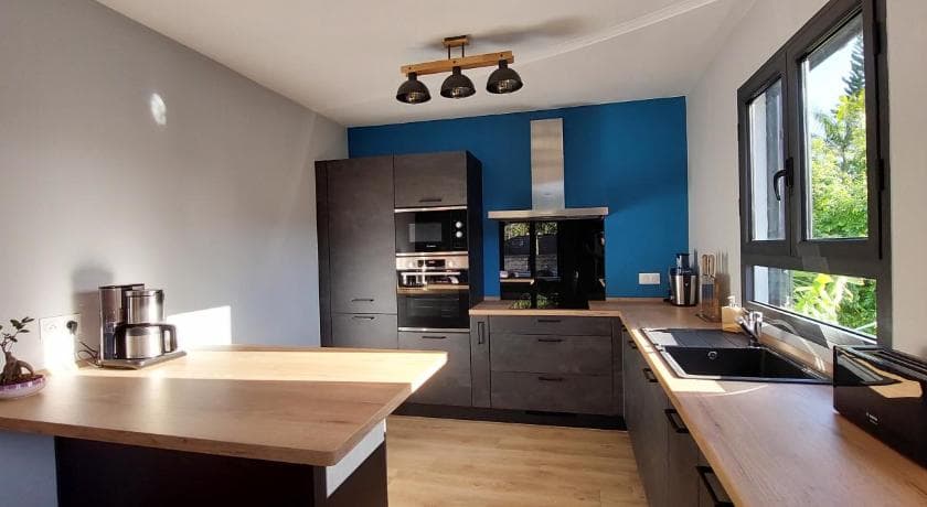 Cuisine équipée de La Villa Tortue, mur bleu et suspensions noires