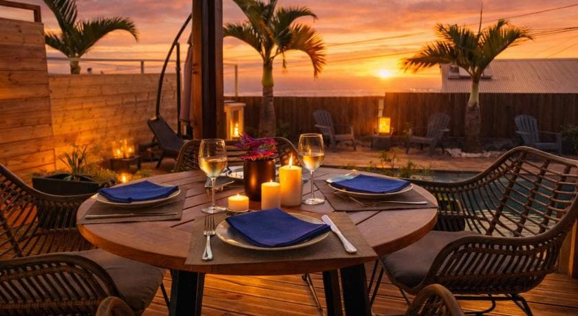 Table dressée aux chandelles sur la terrasse de la Villa des 4 Sens, coucher de soleil entre les palmiers
