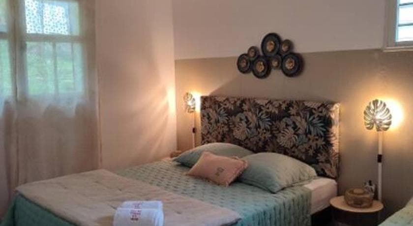 A bedroom at Entre Terre & Mer, a leaf-print headboard and a lit bedside lamp