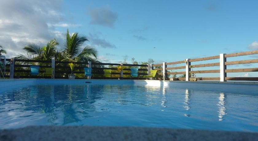 The pool at La Pointe au Corail, edged by a wooden fence, with palms and blue sky