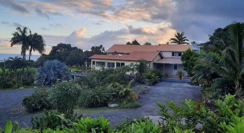 The red-roofed buildings of Ti'planteur farm inn in a tropical garden, evening sky
