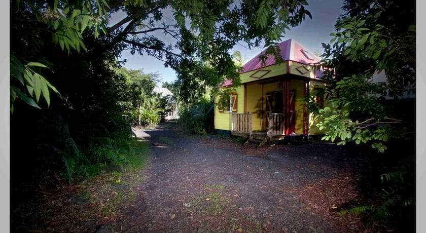 Dan'n Tan Lontan's yellow and pink Creole cottage at the end of a shady path