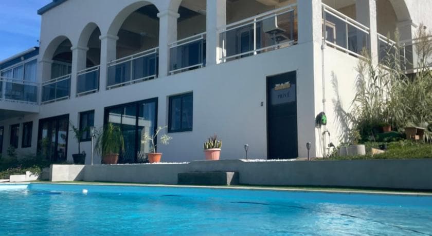 The white arched facade of Villa Blue Lodge above its pool