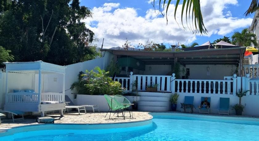 The pool at Le Paille en Queue, loungers, palms and a house with white railings