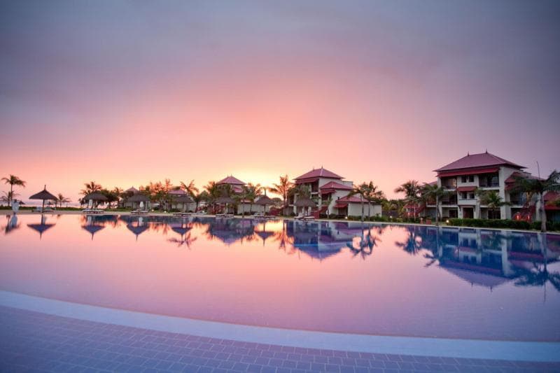 Bâtiments du Tamassa reflétés dans la piscine au coucher du soleil, ciel rose
