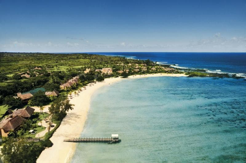Vue aérienne du Shanti Maurice, villas sous les arbres le long d'une plage de sable blanc et d'un lagon