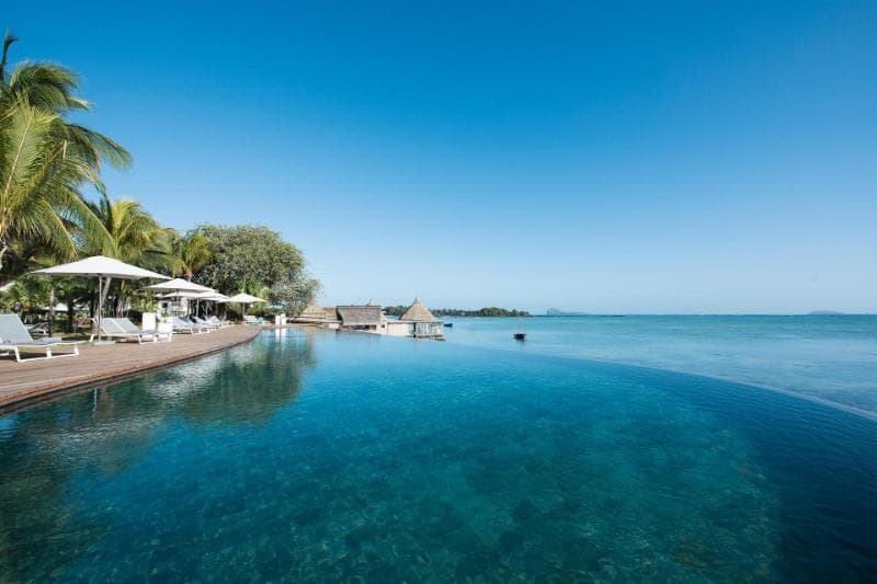 The infinity pool at Veranda Paul et Virginie merging into the lagoon, loungers under parasols