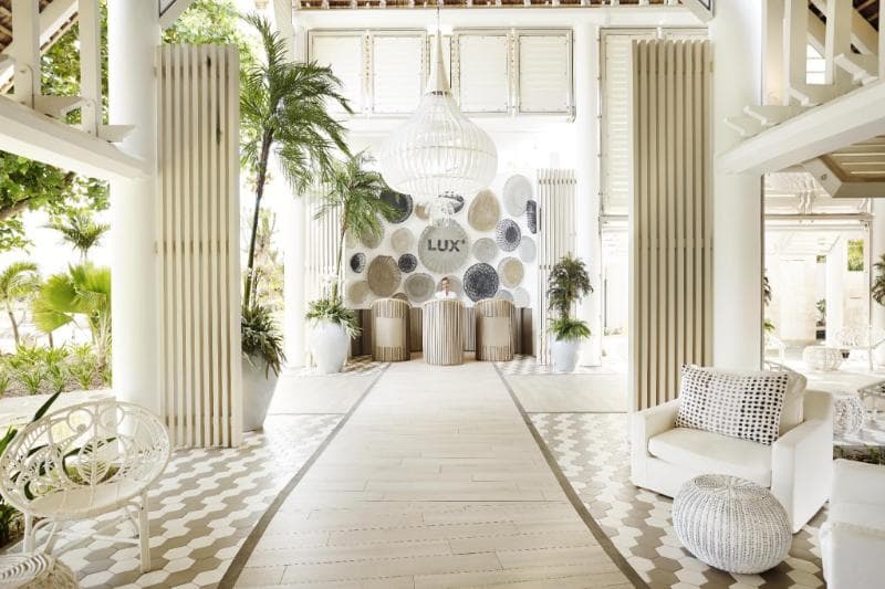 The white lobby at LUX* Grand Gaube, with a chequered floor, columns and pale armchairs
