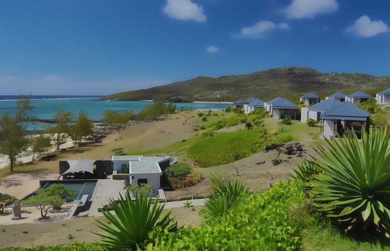 Tekoma's grey-roofed Creole villas by the lagoon, a green hill behind