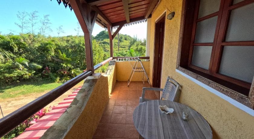 The tiled veranda at Gîte Le Tropical with a table and chairs, greenery below