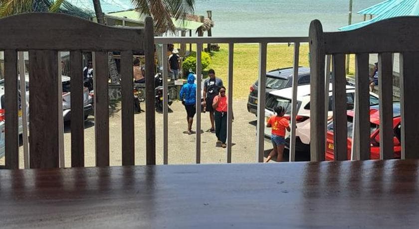 View from a wooden balcony at La Plage Residence over the street and parking, the lagoon beyond