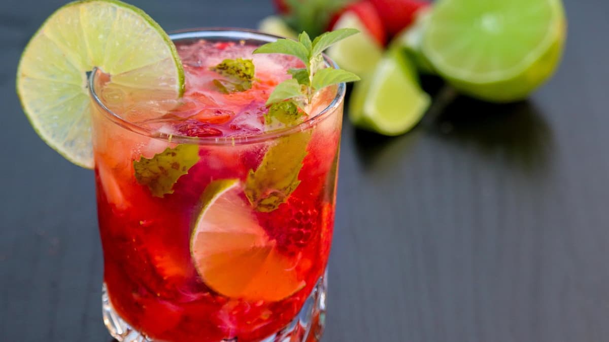 Cocktail rouge au rhum garni de citron vert et de feuilles de menthe